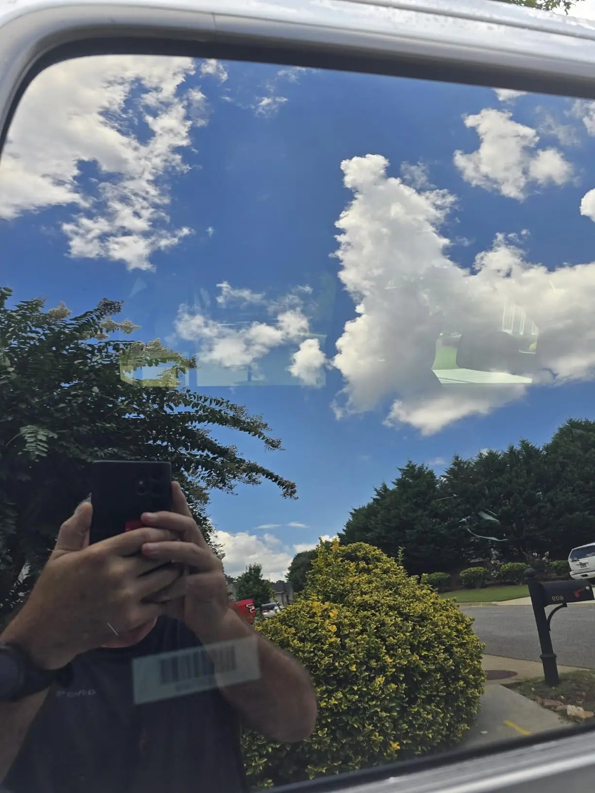 Clean car side window reflecting blue sky and clouds after using Kapak glass cleaner
