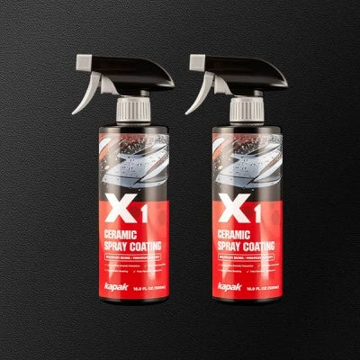 Two Kapak X1 ceramic spray coating bottles on dark background