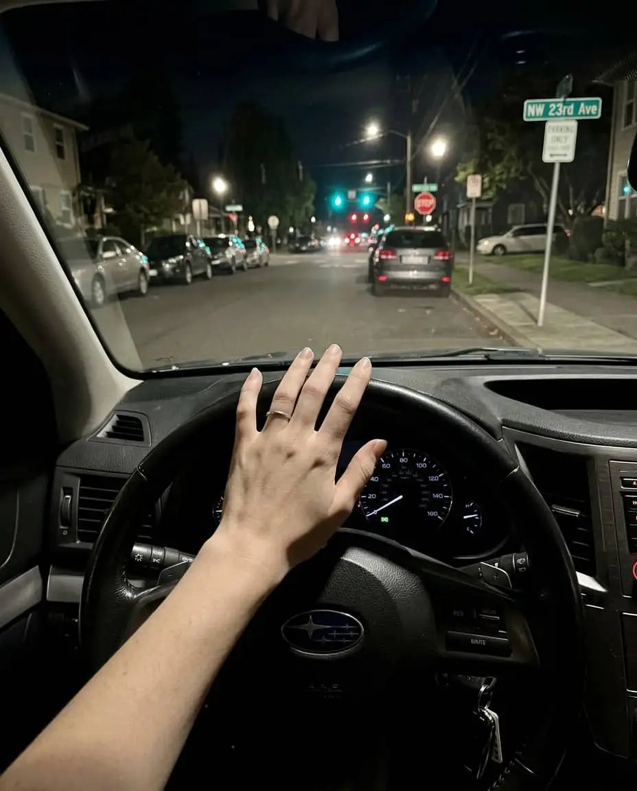 Night driving view from driver seat with hand on steering wheel and clear windshield visibility